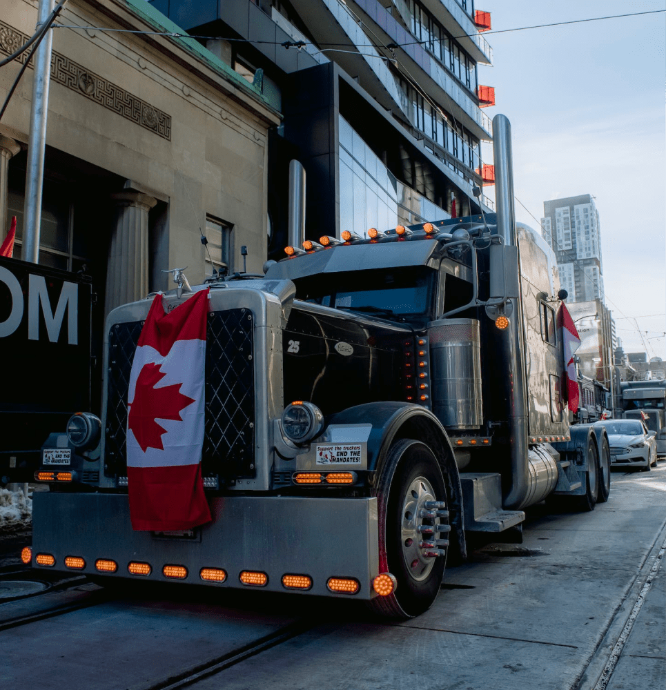 large truck in a crowded street with the canadian flag on its front